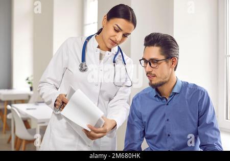 Médecin de sexe féminin montrant les résultats des tests à un patient de sexe masculin dans une clinique médicale Banque D'Images