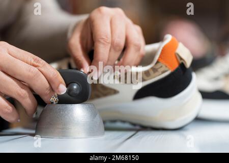 Un employé du magasin de vêtements retire l'alarme d'un vêtement Banque D'Images