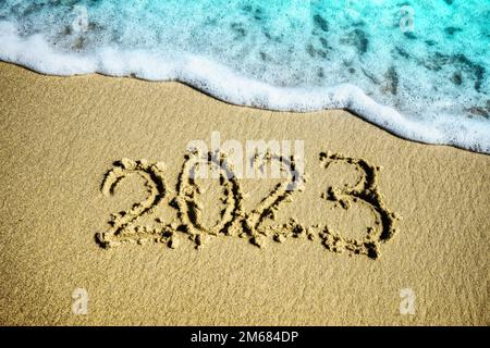 Concept de bonne année. Inscription 2023 sur la plage de sable avec vague Banque D'Images