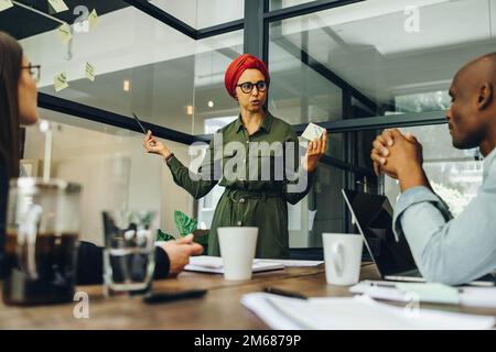 Le chef d'équipe partage ses idées créatives avec son équipe au cours d'une réunion. Femme d'affaires musulmane utilisant des notes adhésives lors d'une discussion. femme d'affaires nous Banque D'Images