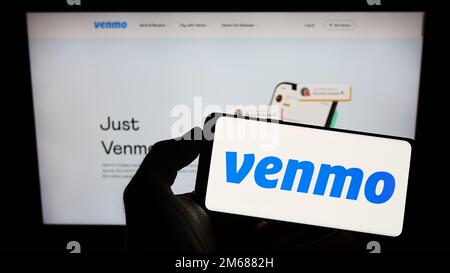 Personne tenant smartphone avec logo du service de paiement mobile Venmo sur l'écran devant le site Web. Mise au point sur l'affichage du téléphone. Banque D'Images