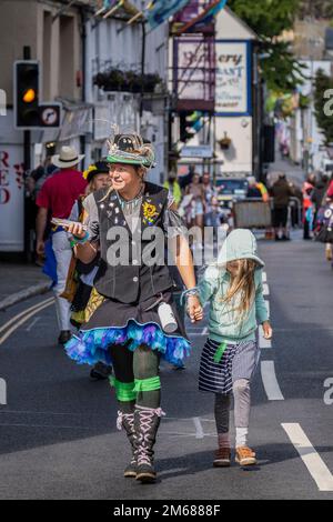 Un membre de la marche des Pensans Morris tenant la main avec un jeune enfant lors de la partie de jour de Mazey du Golowan Festival à Penzance dans Cornwall dans l'U Banque D'Images