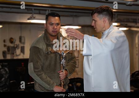 LE chef principal de la circulation aérienne de LA MER DES PHILIPPINES (17 avril 2022), Arvie Raymundo, de Manille (Philippines), à gauche, et le lieutenant Luke Dundon, de Chantilly (Virginie), se préparent au service de Pâques catholique à bord du porte-avions de la classe Nimitz USS Abraham Lincoln (CVN 72). Abraham Lincoln Strike Group est en cours de déploiement prévu dans la zone d'exploitation de la flotte américaine 7th afin d'améliorer l'interopérabilité par le biais d'alliances et de partenariats tout en servant de force de réaction prête à l'emploi pour soutenir une région libre et ouverte d'Indo-Pacifique. Banque D'Images