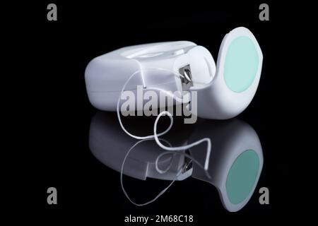 Contenant avec fil dentaire. Soie dentaire sur fond noir. Boîtier de fil dentaire blanc isolé. Ouvrir le contenant de fil dentaire. Banque D'Images