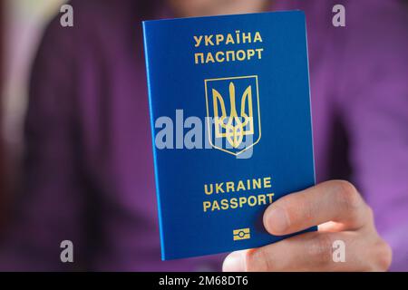 Nouveau passeport biométrique bleu ukrainien avec puce d'identification en mains. Banque D'Images