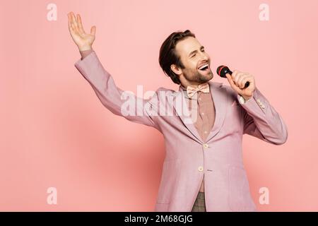 Brunette hôte de l'événement chantant au microphone sur fond rose, image de stock Banque D'Images