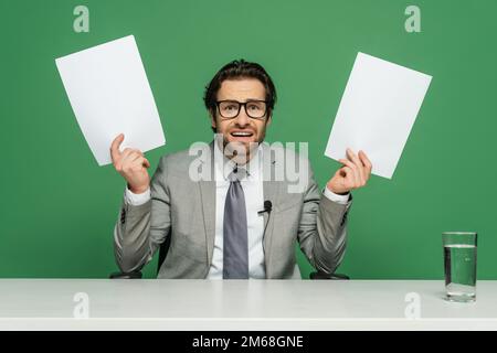 nouvelles émotionnelles ancre dans les lunettes et costume tenant des papiers vierges isolés sur vert, image de stock Banque D'Images