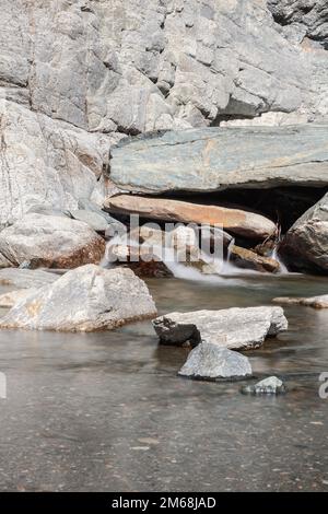 Eau floue en longue exposition et flaque avec de petits cailloux et sables sur le fond formé par la cascade de Lillaz (Cascate di Lillaz) vallée d'Aoste Banque D'Images