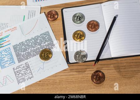 KIEV, UKRAINE - 17 NOVEMBRE 2022 : vue de dessus des bitcoins sur le carnet vide près du stylo et des documents sur le bureau Banque D'Images