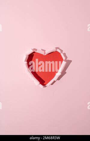 Cœur rouge en papier rose déchiré. Un minimum d'amour ou de valentine concept. Banque D'Images