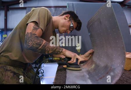 Les aviateurs principaux Sean Olson, mécanicien d'atelier d'entretien structural d'aéronef du 920th Escadron de maintenance, sables de protection une feuille de métal; la préparer avant d'appliquer un revêtement protecteur après qu'un roi de combat HC-130J II a rencontré une attaque d'oiseau et a dû faire l'objet de réparations à la base de la Patrick Space Force, Floride, 19 avril 2022. Banque D'Images