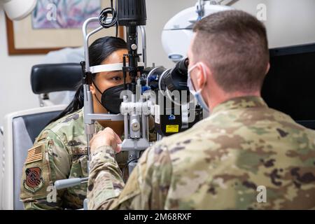 Le capitaine Dominic Rentz, optométriste de l'escadron de préparation médicale opérationnelle 15th, examine les yeux du 1st lieutenant Denise Guaio-Corpuz, chef des Affaires publiques de la 15th e Escadre, lors d'un examen oculaire de routine à la base conjointe Pearl Harbor-Hickam, Hawaii, 19 avril 2022. Les techniciens en optométrie aident à diagnostiquer les troubles oculaires et aident les aviateurs à porter des lunettes, tout en jouant un rôle essentiel dans l'aide aux patients pour leur santé oculaire. Banque D'Images