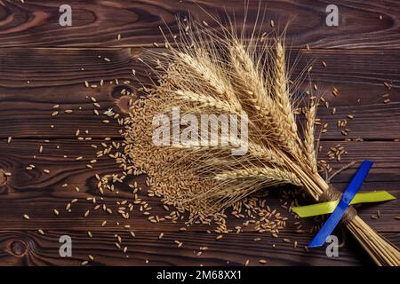 Épis de blé mûr avec drapeau ukrainien. grains épars sur une planche de bois Banque D'Images