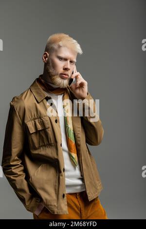 albinos barbu dans la veste de chemise parlant sur smartphone isolé sur gris, image de stock Banque D'Images