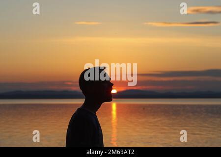 Région de Chelyabinsk, Russie - 12 juillet 2019. Un gars sympa sur fond de coucher de soleil sur le lac. Banque D'Images