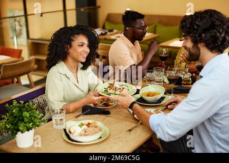 Un ami multiculturel dîne avec des amis dans un restaurant. Banque D'Images