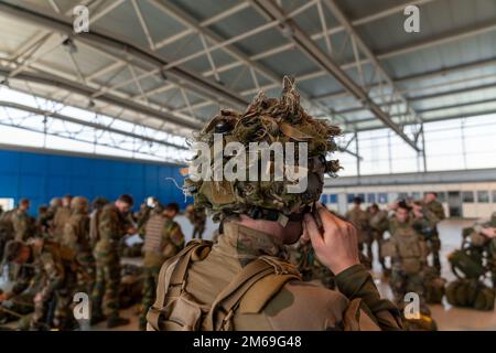 Un parachutiste français affecté au Régiment des parachutistes d'infanterie marine 8th, Brigade de parachutistes 11th, pond son casque alors qu'il se prépare pour un saut aux côtés des parachutistes belges affectés au Bataillon du Commando 2nd, Régiment des opérations spéciales, pendant l'opération Nemesis, sur la base aérienne de Chièvres, Belgique, 20 avril 2022. Opérations Nemesis était un exercice conjoint de plusieurs jours entre les forces belges et françaises, qui se sont déployées à partir de la base aérienne de Chièvres pour exécuter des missions dans plusieurs endroits du pays. Banque D'Images