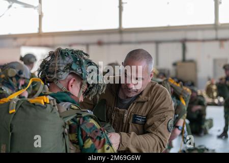 Un répartiteur (Jumpmaster) affecté au centre d'entraînement ce-Para vérifie le gréement des parachutistes belges affectés au bataillon du Commando 2nd, Régiment des opérations spéciales, alors qu'ils préparent un saut pour l'opération Nemesis, sur la base aérienne de Chièvres, Belgique, 20 avril 2022. Opérations Nemesis était un exercice conjoint de plusieurs jours entre les forces belges et françaises, qui se déployaient de la base aérienne de Chièvres à plusieurs endroits en Belgique. (É.-U. Photo armée -nametag flou pour des raisons de sécurité -par Pierre-Etienne Courtejoie) Banque D'Images