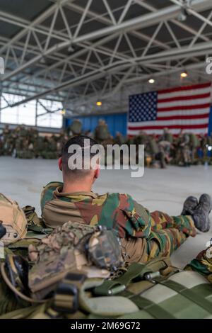 Un parachutiste belge reste après une mission et regarde un autre groupe de ses pairs, affecté au bataillon du Commando 2nd, Régiment des opérations spéciales, complété par les parachutistes français du Régiment des parachutistes d'infanterie marine 8th, Brigade de parachutistes 11th, se préparer à un saut lors de l'opération Nemesis, sur la base aérienne de Chièvres, Belgique, 20 avril 2022. Opérations Nemesis était un exercice conjoint de plusieurs jours entre les forces belges et françaises, qui se sont déployées à partir de la base aérienne de Chièvres pour exécuter des missions dans plusieurs endroits du pays. Banque D'Images