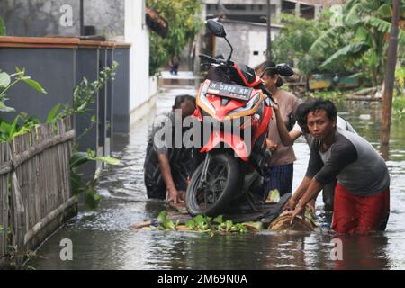 Semarang, Indonésie. 3rd janvier 2023. Les gens transfèrent une moto avec un radeau en bois à travers les eaux d'inondation dans un village de Semarang, Central Java, Indonésie, 3 janvier 2023. Credit: Rahman Indra/Xinhua/Alamy Live News Banque D'Images