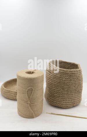 Sac tricoté jute un panier en cours de travail, un crochet à tricoter et un fil de jute babina sur une table en bois blanc Banque D'Images