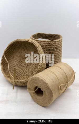 Sac tricoté jute un panier en cours de travail, un crochet à tricoter et un fil de jute babina sur une table en bois blanc Banque D'Images
