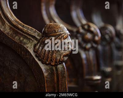 Visages sculptés sur les accoudoirs du treizième siècle Early English stalles du choeur de l'abbaye de Hexham, Northumberland, Angleterre Banque D'Images