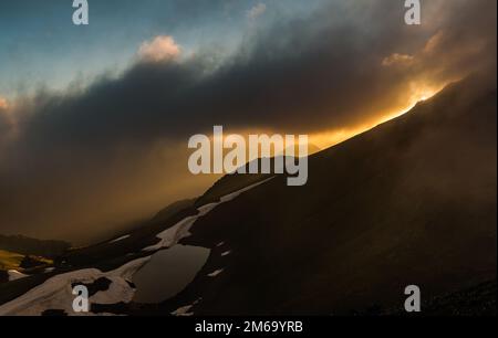 Coucher de soleil sur le lac de montagne. Paysage du soir. Photo à travers les nuages. Montagnes du Caucase. Karachay-Cherkessia. Russie. Banque D'Images