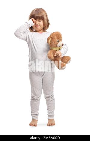 Enfant en pyjama tenant un ours en peluche et les yeux frottant isolés sur fond blanc Banque D'Images