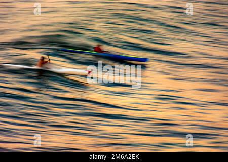 Canoë sur la vague au coucher du soleil dans la mer de la ville de Salvador à Bahia avec des mouvements flous et des personnes méconnaissables Banque D'Images