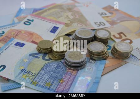 Image des billets de 10, 20 et 50 euros sur lesquels il y a des pièces en cent et en euros sur une table blanche Banque D'Images