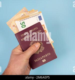 Un passeport italien avec des billets en euros à l'intérieur de la main d'un homme Banque D'Images