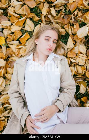 portrait d'une jeune femme couché sur les feuilles et regardant l'appareil photo Banque D'Images