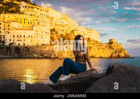 femme assise sur les rochers contre les maisons blanches de la côte amalfitaine Banque D'Images