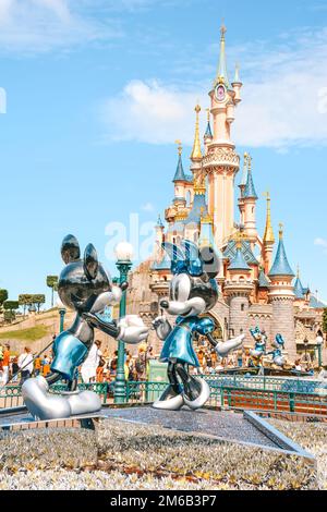 Une photo verticale de la vue sur Disneyland avec un château de conte de fées derrière la statue de la mickey et Minnie à Paris, France Banque D'Images