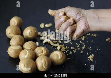 Préparation de la laddu de Moong dal sous forme de balle avec la main. Il est riche en protéines, sucré indien fait de lentilles, d'amandes et de jaggery comme édulcorant. Prise de vue en wi Banque D'Images