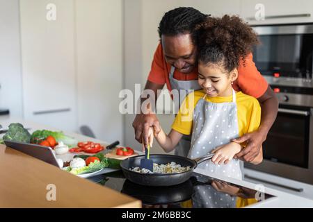 Papa noir attentionné enseignant à sa fille de préadolescence cuisine de la nourriture à la maison Banque D'Images