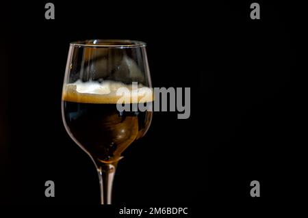 Bière foncée dans un verre sur fond noir. Un arrière-plan intéressant pour les boissons. Banque D'Images