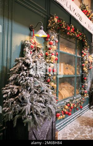 Café extérieur de boulangerie avec des décorations festives pain frais, croissants, en verre vitrine pâtisserie rétro vintage confortable à Noël nouvel an soir en plein air ne Banque D'Images