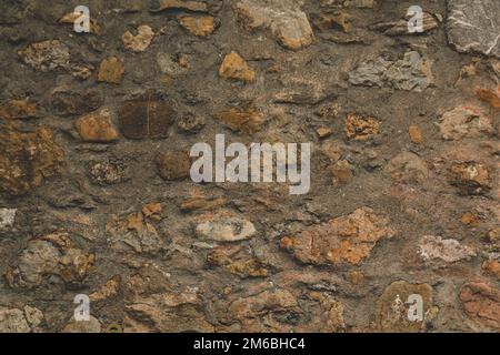 Mur en pierre à galets rocailleux avec mortier pour un arrière-plan texturé matériau abstrait légèrement sale vintage et non uniforme Banque D'Images