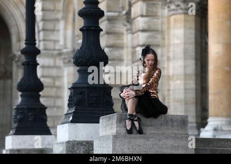 Ballerine élégante en jupe noire, brume et or haut assis seul en face d'un palais Banque D'Images
