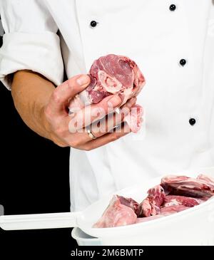 Un chef professionnel en veste, tenant un morceau de viande rouge Banque D'Images