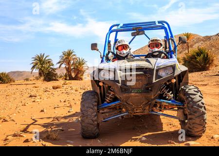 Merzouga, Maroc - 26 févr. 2016: Vue de face sur le bleu Polaris RZR 800 avec ses pilotes dans le désert marocain près de Merzouga. Merzouga Banque D'Images