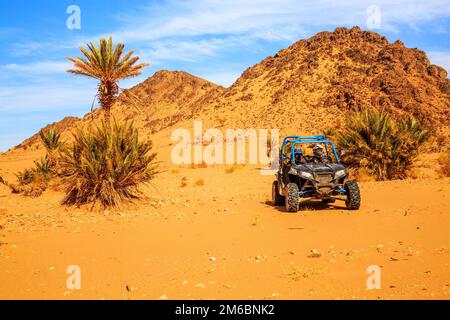 Merzouga, Maroc - 26 févr. 2016: Vue de face sur le bleu Polaris RZR 800 avec ses pilotes dans le désert marocain près de Merzouga. Merzouga Banque D'Images