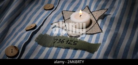 Étoile David et bougie brûlante sur robe de prisonnier. Journée internationale de commémoration de l'Holocauste Banque D'Images