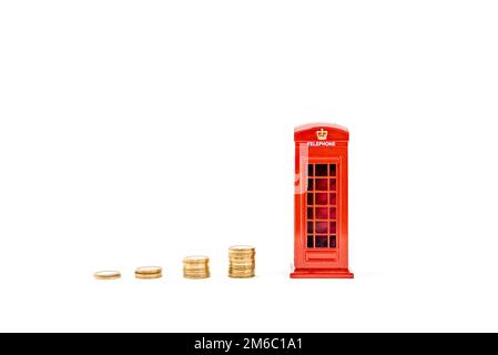 Cabine téléphonique rouge avec des pièces de monnaie empilées money Box london, Penny ou piggy Bank sur fond blanc. Idée de réaliser des économies photo hd. Boîte à économie d'argent. Banque D'Images