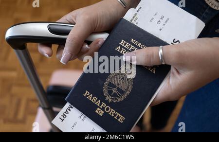 Jeune fille montrant le passeport argentin avec ses sacs de voyage. Traduction: 'Pasaporte' signifie Passeport. 'Cercosur: República Argentina' signifie Mercosur Banque D'Images