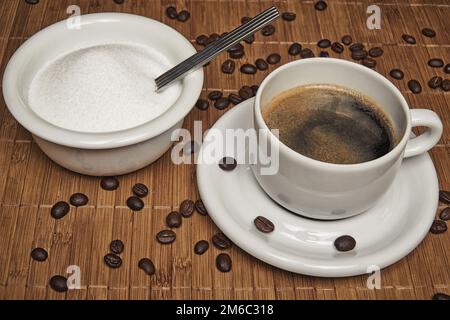 Tasse de café frais entouré par des grains de café et sucre sur un fond de bois - filtre anti-pop Banque D'Images