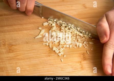 Man's hands cutting l'ail frais dans la cuisine, préparer un repas pour le déjeuner. Avec copyspace. Banque D'Images