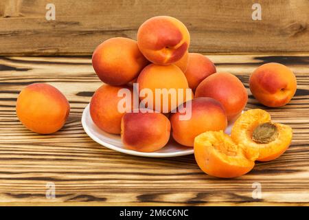 Sur une table en bois et sur une soucoupe blanche se trouvent des abricots mûrs Banque D'Images